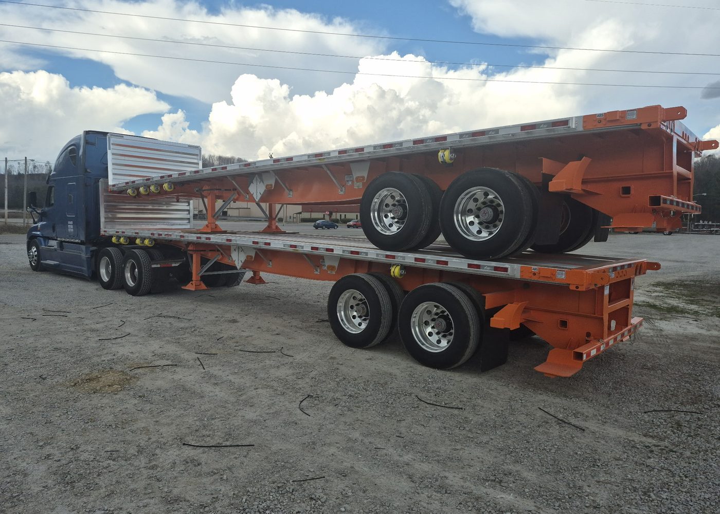 A tractor coupled to flatbed trailers in a yard.