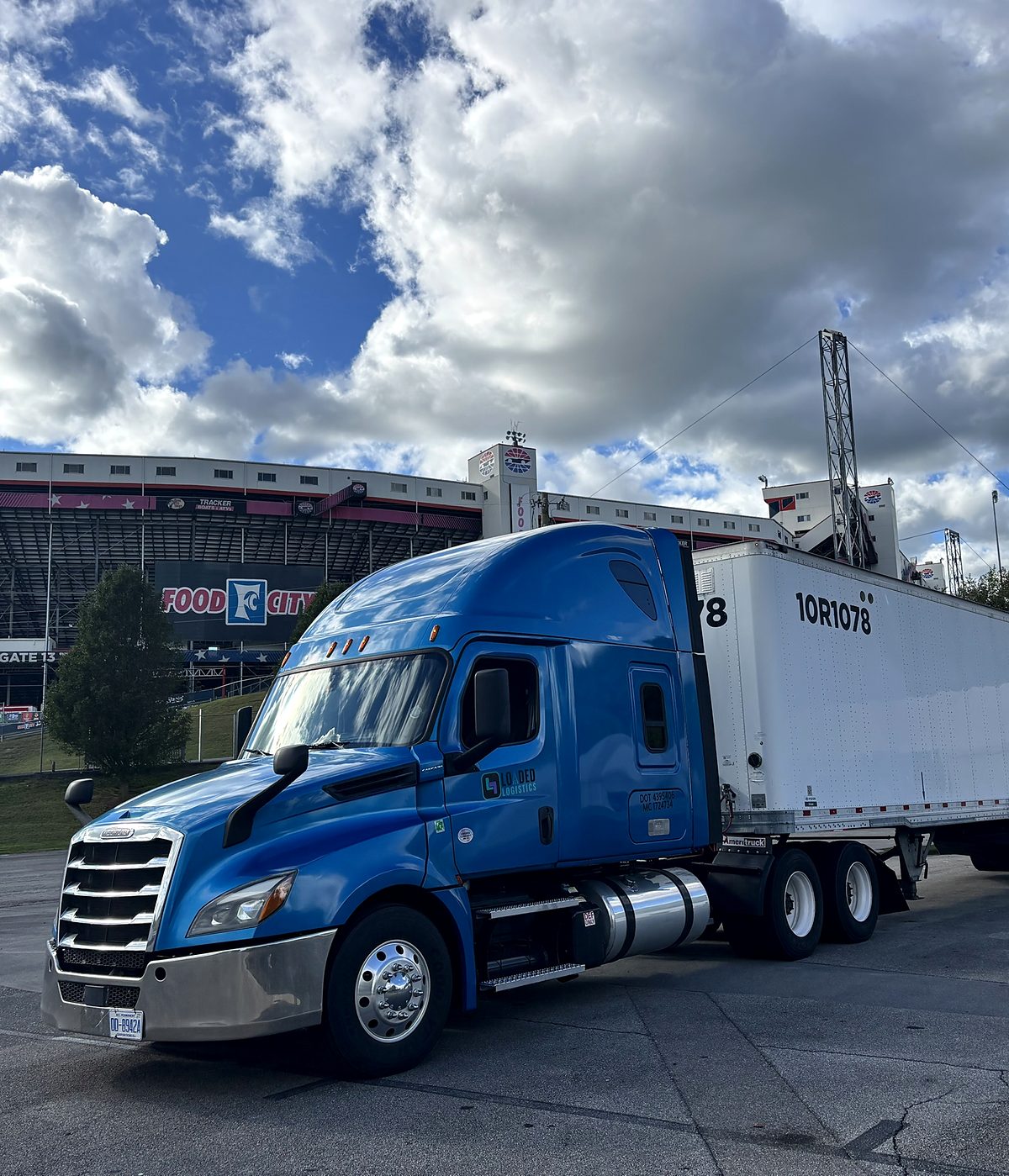 The Loaded Logistics Freightliner Cascadia hooked to a 53-foot dry van, parked outside a motor speedway.